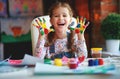 Funny child girl draws laughing shows hands dirty with paint Royalty Free Stock Photo