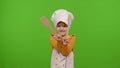 Funny child girl kid dressed cook chef baker in apron and hat dancing, fooling around, making faces