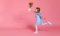 Funny child girl runs and jumps with bouquet of flowers on color