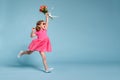 Funny child girl runs and jumps with bouquet of flowers on color