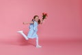 Funny child girl runs and jumps with bouquet of flowers on color Royalty Free Stock Photo