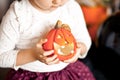 funny child girl in witch costume for Halloween holding a pumpkin lantrern