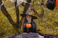 Funny child girl in a witch costume for Halloween holds a mug in the form of a pumpkin.