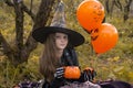 Funny child girl in a witch costume for Halloween holds a mug in the form of a pumpkin.