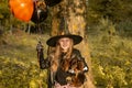 Funny child girl in a witch costume for Halloween with a small dog and with black and orange balloons. Royalty Free Stock Photo