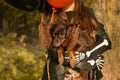 Funny child girl in a witch costume for Halloween with a small dog and with black and orange balloons. Royalty Free Stock Photo