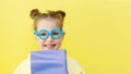 Funny child girl yellow jacket on a yellow background, sitting, reading a book, development and school concept Royalty Free Stock Photo