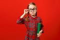 Funny child in glasses and with a book on a red background. Portrait of a serious smart little girl Royalty Free Stock Photo
