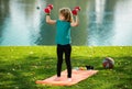 Funny child lifting the dumbbells in backyard outside. Kids in training.