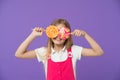 Funny child with lollipops on violet background. Girl smiling with candy eyes. Little kid smile with candies on sticks Royalty Free Stock Photo