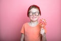 Funny child looking on big lollipop on pink background. Cute eight years boy with close eyes and candy in hand. Happy Royalty Free Stock Photo