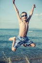 Funny child playing in sea splashing water and jumping.