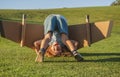 Funny child playing upside down with toy plane wings in summer park. Innovation technology and success concept. Kid Royalty Free Stock Photo