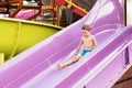 Funny child playing in water park splashing water. Summer holidays concept. Boy has into pool after going down water slide during Royalty Free Stock Photo