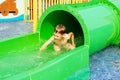 Funny child playing in water park splashing water. Summer holidays concept. Boy has into pool after going down water slide during Royalty Free Stock Photo