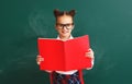 Funny child   schoolgirl girl student with book about school blackboard Royalty Free Stock Photo