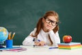 Funny child schoolgirl girl student sitting at table near school blackboard