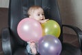 Funny child sitting on chair little boy having fun playing big colored balloons Royalty Free Stock Photo