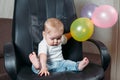 Funny child sitting on chair little girl having fun playing big colorful balloons Royalty Free Stock Photo