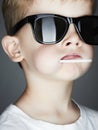 Funny child in sunglasses eating lollipop Royalty Free Stock Photo