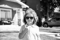 Funny child in sunglasses with thumbs up sign close up. Kids outdoor home, near house, head portrait.