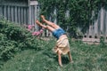 Funny child teenage girl doing cartwheel on a backyard. Excited joyful kid playing outdoor. Happy lifestyle childhood and freedom Royalty Free Stock Photo