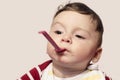 Funny child trying to feed himself baby food holding the spoon in the mouth. Royalty Free Stock Photo
