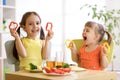Funny children girls eating healthy food. Kids lunch at home or kindergarten.