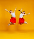 Funny children girls twins jumping on colored yellow background