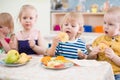 Funny children group eating fruits in kindergarten dinning room Royalty Free Stock Photo
