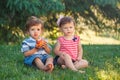 Funny children toddlers sitting together sharing apple food