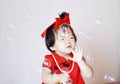 Funny Chinese little baby in red cheongsam play soap bubbles