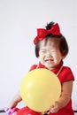 Funny Chinese little baby in red cheongsam play yellow balloon