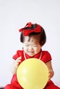 Funny Chinese little baby in red cheongsam play yellow balloon