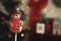 Funny chocolate snowman candy against blurred Christmas tree, closeup. Space for text Royalty Free Stock Photo