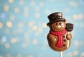Funny chocolate snowman candy against blurred festive lights, closeup. Space for text Royalty Free Stock Photo