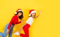 Funny Christmas banner with side view of two mixed race smiling women on one leg in runner position wearing Santa Claus hat -
