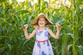 Funny close-up portrait of a little girl in a hat, holding her hair with her hands, in a cornfield Royalty Free Stock Photo