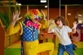 Funny clown animator and boy fooling around playing at indoor playroom