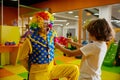 Funny clown animator and boy fooling around playing at indoor playroom