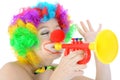 Funny clown with make up makes music with toy trumpet in studio Royalty Free Stock Photo