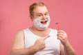 Happy plump man with shaving foam on his face and razor isolated on pink Royalty Free Stock Photo