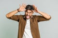 Funny comical Indian man making silly facial expressions, grimacing, fooling around, showing tongue