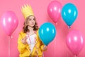 Funny conceptual photography. Cheeky girl in birthday hat holding needle pretending to pop birthday balloons. Celebrating birthday