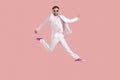 Full length shot of funny young man in suit jumping high in the air isolated on pink background Royalty Free Stock Photo