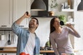 Joyful young family couple having fun singing at home kitchen Royalty Free Stock Photo