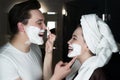 Funny couple beautiful woman applying jokingly foam on handsome man`s nose having fun both with shaving foam on their faces in Royalty Free Stock Photo