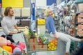 Young happy man pushing shopping trolley with his girfriend in mall Royalty Free Stock Photo