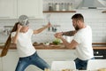 Funny couple having fun fighting with kitchen utensils cooking t Royalty Free Stock Photo