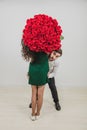 Funny couple joking and fooling with bouquet of red roses over white background. Royalty Free Stock Photo